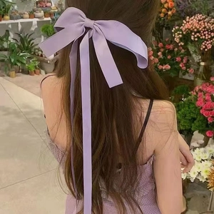 Detailansicht einer lila Satin-Haarschleife mit langen Bändern getragen im Garten