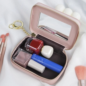 Portable pink mini cosmetic bag with mirror and keychain on white fabric background