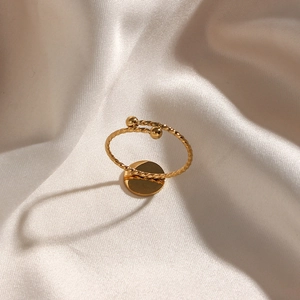 Detail of twisted 18K gold plated ring with beads on a soft silk background
