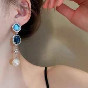 Gros plan sur des boucles d'oreilles perles gouttes françaises avec pierres bleues