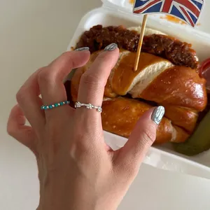 Detailed view of 925 silver floral ring and turquoise bead ring on hand in a lifestyle setting
