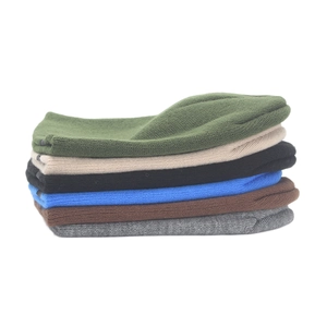 Detailed pile of multi-color knitted beanies in olive, beige, black, and blue tones