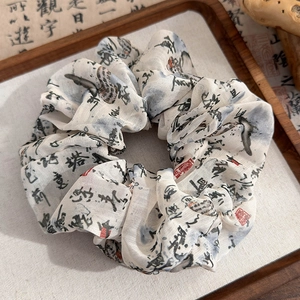 Detail of Chinese ink wash calligraphy and red seal print on a silk scrunchie