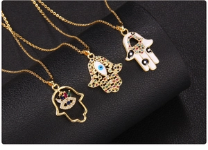 Detailed close-up of three gold Hamsa Hand pendants with colorful zircons and enamel oil