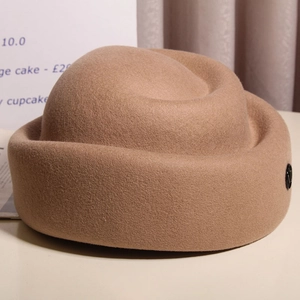 Close-up of elegant camel wool felt pillbox hat showing detailed texture and metal buckle