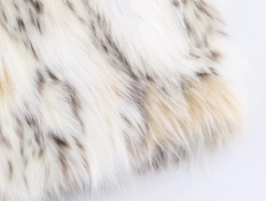 Close-up of snow leopard pattern faux fur texture with soft white and dark brown spots