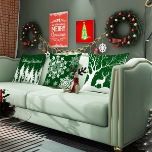 Green Christmas pillow cover with reindeer and tree patterns on a sofa in a festive room
