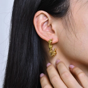 Close-up of golden C-shaped hoop earrings with spiral twisted texture on a female model