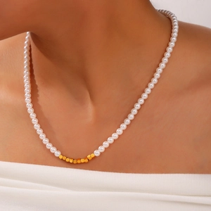Elegant pearl necklace with central gold cube beads on a model, Hepburn style minimalist look