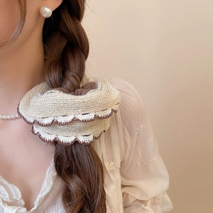 Close-up of knit lace scrunchie in beige and coffee brown worn on a low ponytail