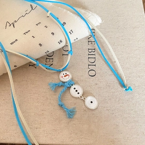Detailed view of snowman pendant necklace with blue scarf decoration and dual colored cords