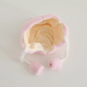 Close-up of pink plush winter hat with faux fur, soft lining and cute hanging pom-poms