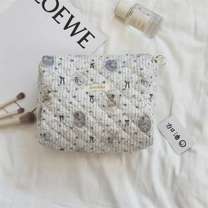 Détail de la trousse de maquillage matelassée avec motif d'ours, nœud et fermeture éclair