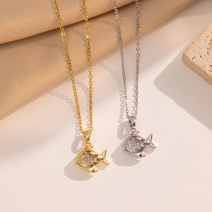Elegant gold and silver fish pendant necklaces with sparkling rhinestones on fabric background