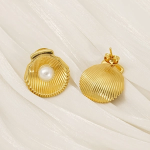 Vue détaillée de boucles d'oreilles coquillage dorées avec perle sur soie blanche