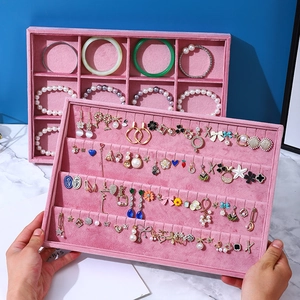 Pink velvet jewelry display tray being held over a white marble surface