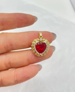 Macro shot of gold-plated heart pendant with vibrant red gemstone and clear zircon halo