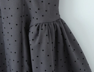 Detail of grey polka dot fabric showing fine pleated texture and stitching craftsmanship