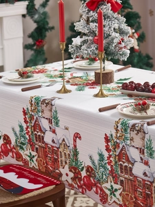 Detalle de mantel navideño con casas de nieve, bastones de caramelo y manteles rojos