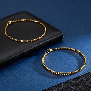 Detail of two gold titanium steel box chain bracelets in different thicknesses on black leather