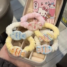 Macro view of six colorful plush fish hair ties in a beige jewelry display box