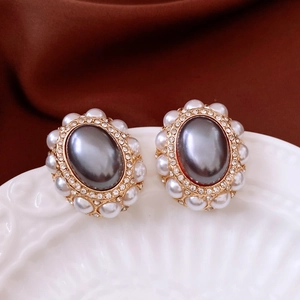Macro view of vintage gold stud earrings with oval faux pearl and crystal halo details