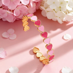 Dettaglio del bracciale aperto dorato a cuore con smalto rosa e accenti floreali eleganti