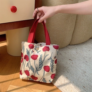 Dettaglio della borsa in tela a fiori rossi con bottone a pressione ed etichetta logo