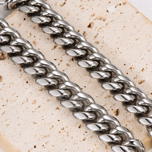 Polished silver stainless steel Cuban link necklace for men on a textured stone background