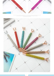 Macro view of crystal encrusted metal ballpoint pens with large diamond top ornaments