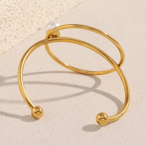 18K gold-plated stainless steel knotted bracelet with white pearl on beige surface