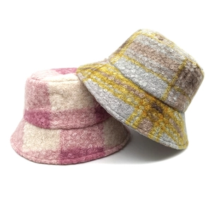 Close-up of thick plaid teddy fleece bucket hats in pink and yellow for winter