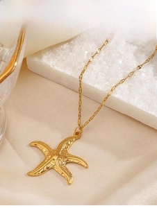 Detailed view of golden starfish pendant necklace with textured finish on silk fabric