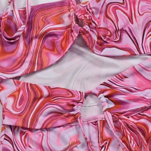 Détail de la robe à imprimé marbre rose montrant le tissu froncé et l'anneau relié
