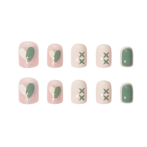 Short square press-on nails with heart glitter and green cross patterns on white background