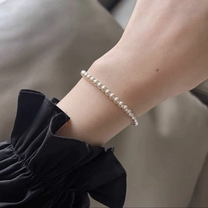 Close-up of elegant 6-7mm natural freshwater pearl ring on woman hand with dark sleeve