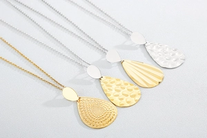 Close-up of teardrop pendants with hammered and stippled textures in gold and silver