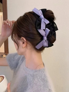 Side view of a large purple and black silk bow hair claw clip worn on a woman's head
