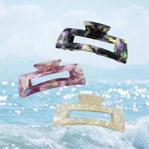 Three elegant acetate hair claw clips with marble pattern on ocean wave background