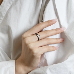 Close-up of a matte black heart ring with zircon stone worn on a finger