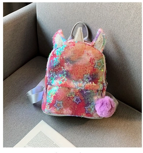 Close-up of rainbow sequin unicorn backpack with silver straps and purple pom-pom detail