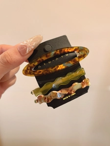Three-piece acetate hair clip set featuring amber and olive green wavy patterns on card