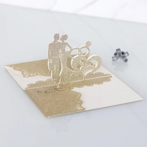 Macro shot of 3D wedding card with gold glitter Mr & Mrs silhouette and rings detail