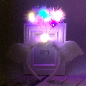 Close-up of white feather angel wing headband with colorful glowing LED lights