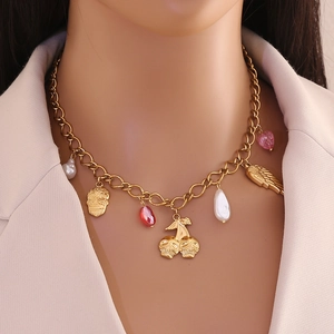 Collier doré avec pendentifs tête de mort, perle, aile et cœur porté par un mannequin