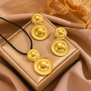 Detail of gold teardrop jewelry set with textured circular pendants on beige silk