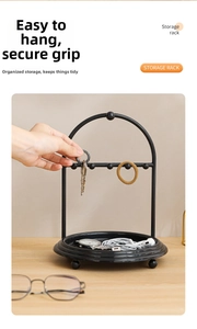 Detail of black metal storage rack with five hanging hooks and a round organizer tray
