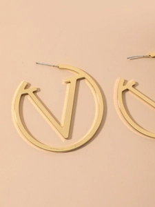 Detailed view of gold hoop earrings featuring a cutout V logo design in minimalist style