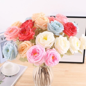 Close-up of colorful silk roses in a glass vase on a wooden table for home decor
