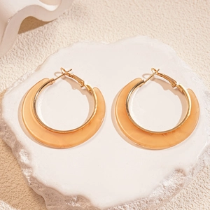 Detail showing amber resin and gold alloy C-shape hoop earrings on textured stone
